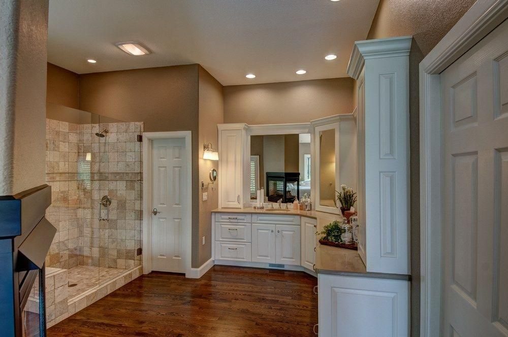 A Plush Designs bathroom with a tiled shower, light cabinetry and a framed mirror