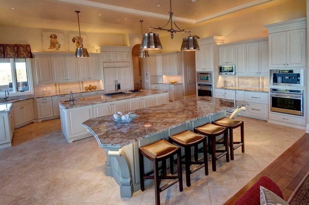 A Plush Designs kitchen with custom cabinetry, a stone island and bar seating