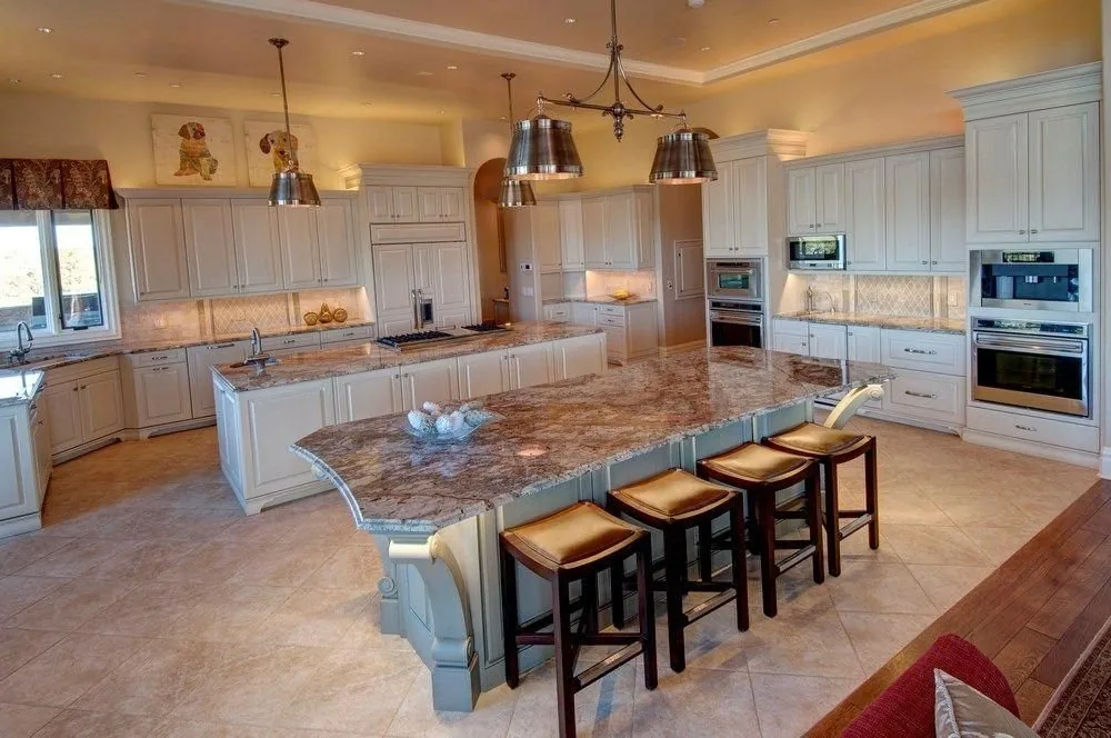 A Plush Designs kitchen with custom cabinetry, a stone island and bar seating