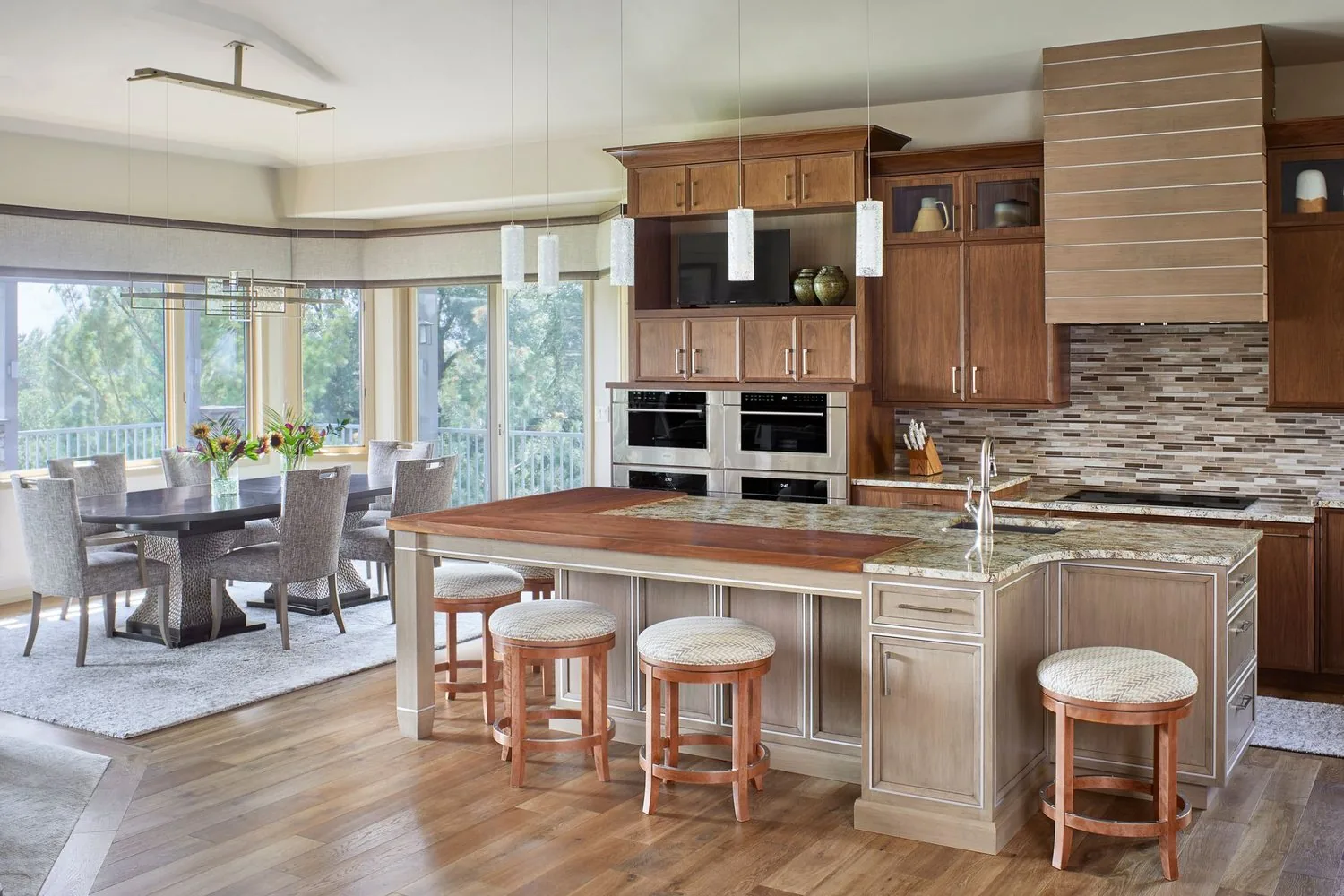 Muirfield Kitchen by Plush Designs, with a wood-topped island, stools and a corner of windows